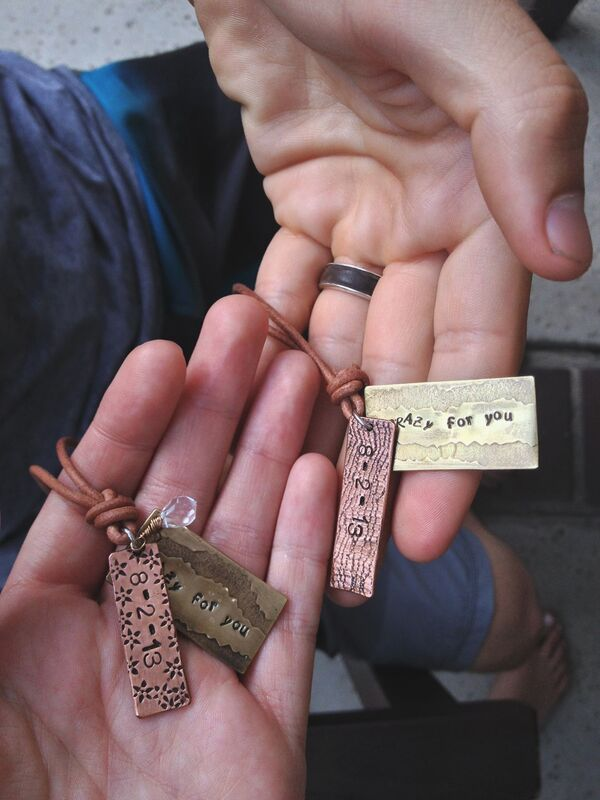 hands holding personalized metal & leather necklaces